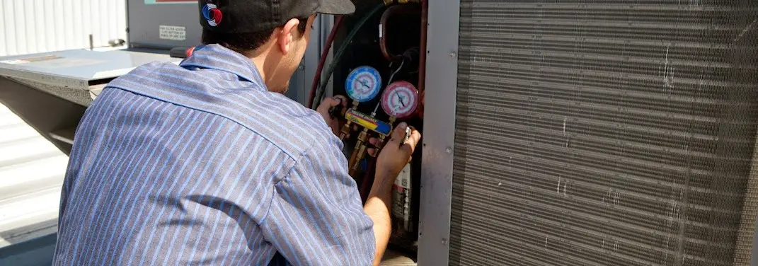 HVAC technician servicing a condenser unit in Kentwood